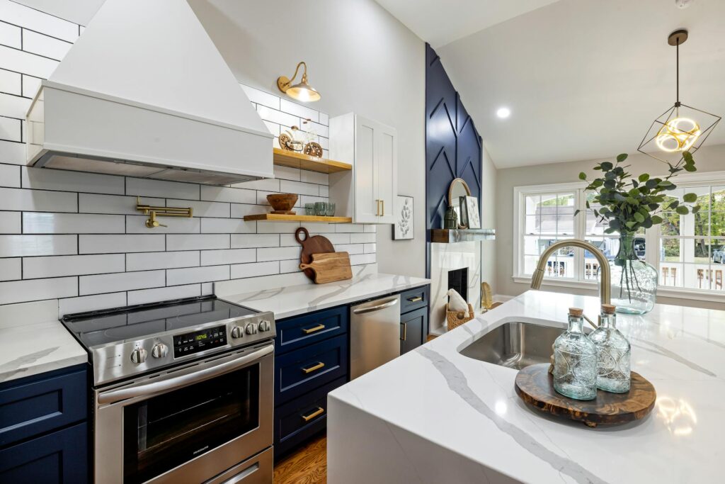 pexels-photo-14495889-14495889 A modern kitchen featuring marble countertops, a stainless steel stove, and elegant blue cabinets.